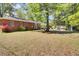 Expansive backyard featuring a well-maintained lawn, mature trees, and a brick home with a back patio at 237 Cypress Dr, Walterboro, SC 29488