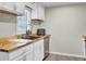 Well-lit kitchen with white cabinets, wood countertops, stainless steel dishwasher, and a dark single basin sink at 237 Cypress Dr, Walterboro, SC 29488