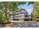 Inviting three-story condo boasts multiple balconies and coastal design, surrounded by mature trees at 2413 Racquet Club Dr, Seabrook Island, SC 29455