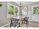 Dining room with modern light fixture, wood table, black chairs, and large windows at 3484 Johan Blvd, Johns Island, SC 29455