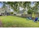 A beautiful backyard with a well-manicured lawn, mature trees, and colorful patio furniture at 41 Regency Oaks Dr, Summerville, SC 29485