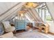Attic bedroom features exposed beams, hardwood floors, a vintage writing desk, and a comfortable seating area at 55 Laurens St # 55-A, Charleston, SC 29401