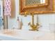 Close-up of bathroom vanity with vintage gold faucet, rattan mirror, and a vessel sink with charming accessories at 55 Laurens St # 55-A, Charleston, SC 29401