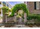 Wrought-iron gate framed by brick pillars covered in vines and foliage at 55 Laurens St # 55-A, Charleston, SC 29401