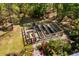 Aerial view of a garden with raised beds, surrounding landscape, sitting area, and vibrant greenery at 5680 Dixie Plantation Rd, Hollywood, SC 29449