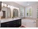 Bright bathroom featuring double sinks, a garden tub, and a glass block shower at 5680 Dixie Plantation Rd, Hollywood, SC 29449