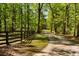 Long, scenic driveway leading through a lush forest, enhanced by a rustic wooden fence at 5680 Dixie Plantation Rd, Hollywood, SC 29449