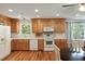 Well-lit kitchen features wooden cabinets, white appliances, hardwood flooring, and a window with a wooded outdoor view at 5680 Dixie Plantation Rd, Hollywood, SC 29449