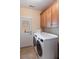 Functional laundry room with modern washer and dryer, cabinets, and tile flooring at 5680 Dixie Plantation Rd, Hollywood, SC 29449