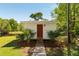 Exterior view of a small white outbuilding with red door and designated delivery signage at 5680 Dixie Plantation Rd, Hollywood, SC 29449