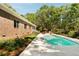 Backyard pool with green trees, brick house, patio furniture and meticulously manicured lawn at 5680 Dixie Plantation Rd, Hollywood, SC 29449
