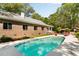 Inviting backyard pool with brick house, patio furniture, and lush green trees at 5680 Dixie Plantation Rd, Hollywood, SC 29449