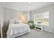 Cozy bedroom with a white bed, a green chair, and a window offering natural light at 5691 Captain Kidd Rd, Hollywood, SC 29449