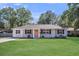 Charming brick home with a lush green lawn and inviting front porch with an orange colored front door at 733 Longfellow Rd, Charleston, SC 29407