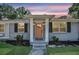 Inviting front entrance with covered porch, orange door, and brick accents surrounded by manicured landscaping at 733 Longfellow Rd, Charleston, SC 29407