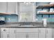 Close-up of a stylish kitchen sink with granite countertops and blue tile backsplash, and open shelving at 733 Longfellow Rd, Charleston, SC 29407