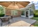A cozy brick back patio area with glass enclosed porch features a table with seating and a large umbrella at 777 Hamlet Cir, Goose Creek, SC 29445