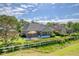 Home backyard with patio, table, seating, lush lawn, white fence and mature trees on a partially cloudy day at 777 Hamlet Cir, Goose Creek, SC 29445