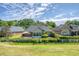 Home backyard with patio, seating, lush lawn, white fence and mature trees under a partially cloudy sky at 777 Hamlet Cir, Goose Creek, SC 29445