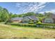 Home backyard with patio, seating, lush lawn, white fence and mature trees on a partially cloudy day at 777 Hamlet Cir, Goose Creek, SC 29445