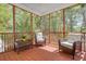 Relaxing screened porch with wood flooring and two comfortable armchairs overlooking the landscaped backyard at 79 Rivers Point, Charleston, SC 29412
