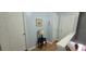 Hallway featuring hardwood flooring, artwork on the blue walls, a table with a lamp, and two white doors at 8107 Old London Rd, North Charleston, SC 29406