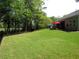 Expansive lawn with mature trees leads to a covered patio and red umbrella, perfect for relaxation at 9677 Islesworth Way, Summerville, SC 29485