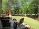 Backyard features lawn, metal fence, trees, and outdoor seating area with seating, umbrella, and fire pit at 9677 Islesworth Way, Summerville, SC 29485