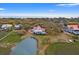 Scenic aerial shot of a house with a red roof near the ocean, surrounded by lush trees and a small lake at 1214 Tabby Dr, Folly Beach, SC 29439