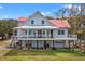 The house features a full porch, complemented by a well-maintained lawn and vibrant landscape at 1214 Tabby Dr, Folly Beach, SC 29439