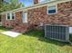 A brick house with a small backyard featuring a door with steps, a window, and an air conditioning unit at 103 Sycamore Dr, Summerville, SC 29485