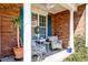 Inviting covered front porch with wicker furniture, lush plants, and brick accents at 106 Sago Palm Ct, Summerville, SC 29483