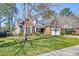 Charming brick home with well-manicured lawn, mature trees, and an American flag displayed on the front porch at 106 Sago Palm Ct, Summerville, SC 29483