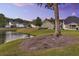 Scenic backyard view with a tranquil pond, lush green grass, mature trees, and a cozy bench by the water's edge at 123 Mcdonald Ct, Summerville, SC 29485
