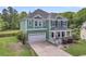 Charming two-story home with green siding, a covered front porch, a well-manicured lawn, and an attached garage at 123 Mcdonald Ct, Summerville, SC 29485