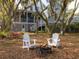 Charming home backyard with a firepit and two chairs with flowers, nestled among mature trees at 1470 Eutaw Battalion Dr, Charleston, SC 29412