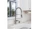 Close up of a kitchen sink with a chrome pull-down faucet, bright window, white cabinets and backsplash at 1470 Eutaw Battalion Dr, Charleston, SC 29412