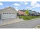 View of detached garage, black metal fence, green lawn, and colorful homes in the distance at 154 Helena Park Dr, Summerville, SC 29486