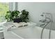Relaxing bathtub with modern fixtures, a convenient book rest, and a view to lush greenery at 155 Wingo Way # 433, Mount Pleasant, SC 29464