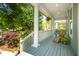 View of the covered front porch, complete with a chair and fern, overlooking landscaped garden at 1977 Pierce St, Charleston, SC 29492