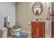 Cozy bathroom with wood vanity, patterned wallpaper, toilet, and round mirror at 2042 Dogwood Rd, Charleston, SC 29414