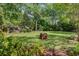Spacious backyard featuring a lush lawn, mature trees, and a cozy fire pit area for outdoor enjoyment at 210 S Gum St, Summerville, SC 29483