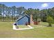 Aerial view of charming blue home with a stone chimney, surrounded by green lawns and woods at 2102 Williams Rd, Ruffin, SC 29475