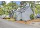 Side view of gray townhouse featuring charming arched windows, surrounded by lush trees and landscaping at 2159 Spoleto Ln # E, North Charleston, SC 29406