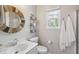 Cozy bathroom with a round wood-framed mirror, white vanity, and a window offering natural light at 2290 Deer Sight Way, Mount Pleasant, SC 29466