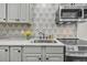 Bright kitchen with stainless steel appliances, gray cabinetry and an artistic tiled backsplash at 24 Hanover St, Charleston, SC 29403