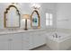 Bright bathroom featuring a double vanity, marble countertop and tub under a shuttered window at 2405 Louisville St, Charleston, SC 29492