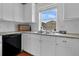 Well-lit kitchen with white cabinets, granite countertops, stainless steel sink, and view of the backyard at 2405 Louisville St, Charleston, SC 29492