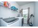 Bright laundry room with modern gray washing machine and dryer, storage shelves, and view to the yard at 249 Oak View Way, Summerville, SC 29483
