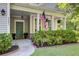 Inviting front porch with American flag, decorative lanterns, and neatly trimmed shrubs at 3001 Grand Bay Ln, Johns Island, SC 29455